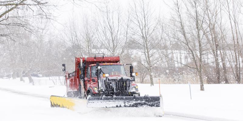 Red snow plow plowing snow off the road