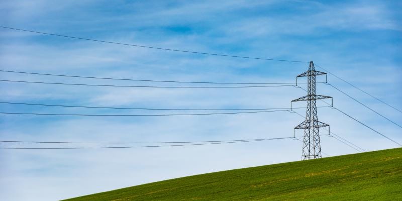 Power lines surrounded by green grass and blue skies