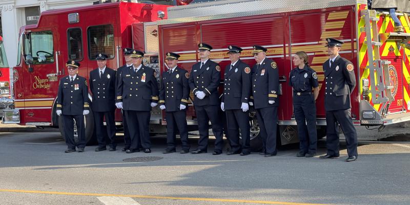 Fire fighters standing in uniform in front of a fire truck