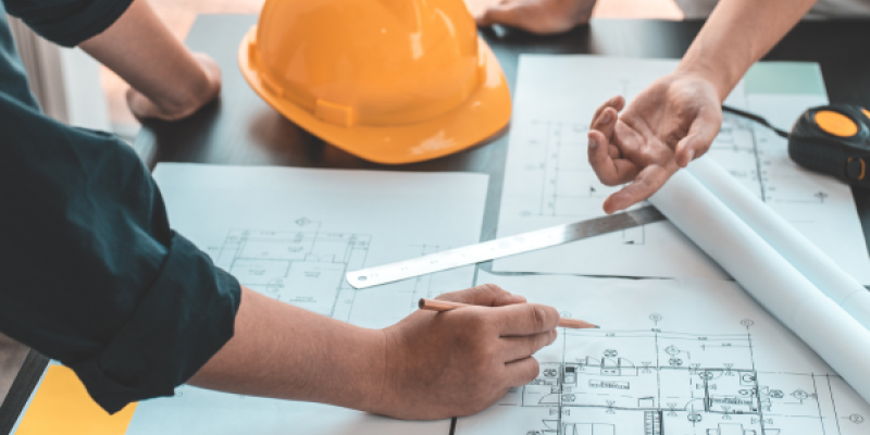 people leaning over building and planning documents