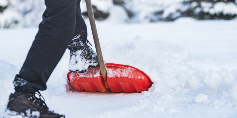 A volunteer helping to shovel a residents driveway