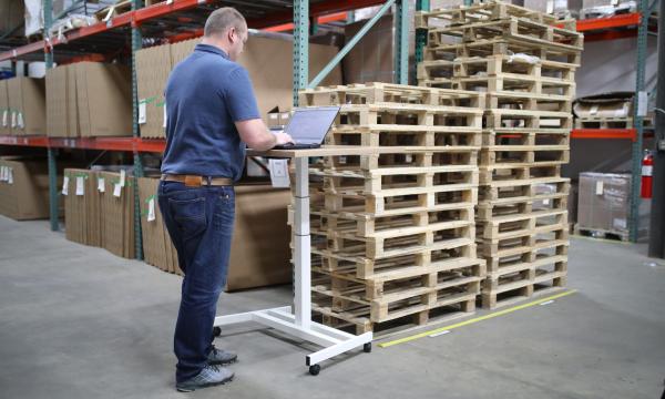Man standing at a computer desk in a warehouse