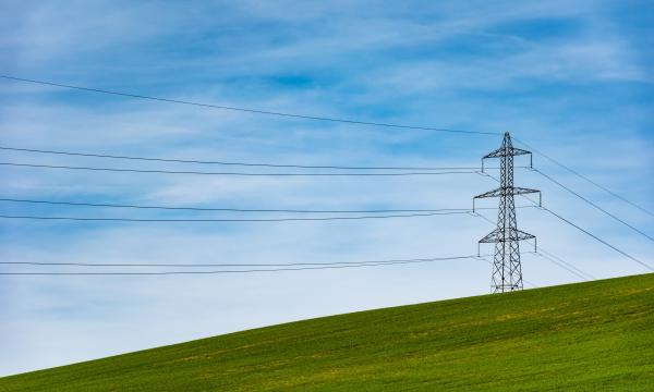 Power lines surrounded by green grass and blue skies