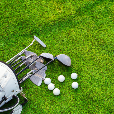 Image of golf clubs and golf balls lying on grass.